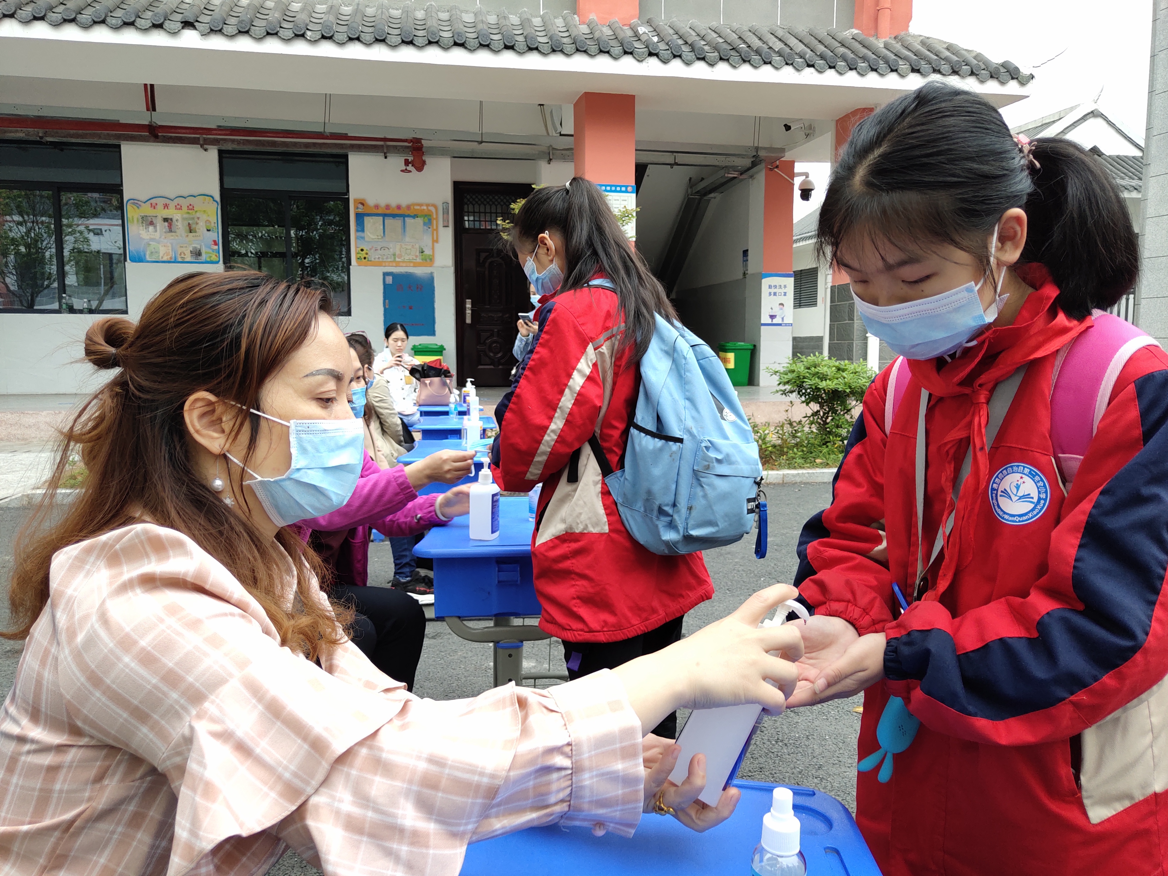 一名老师在指导学生用免洗手液进行手部消毒.jpg