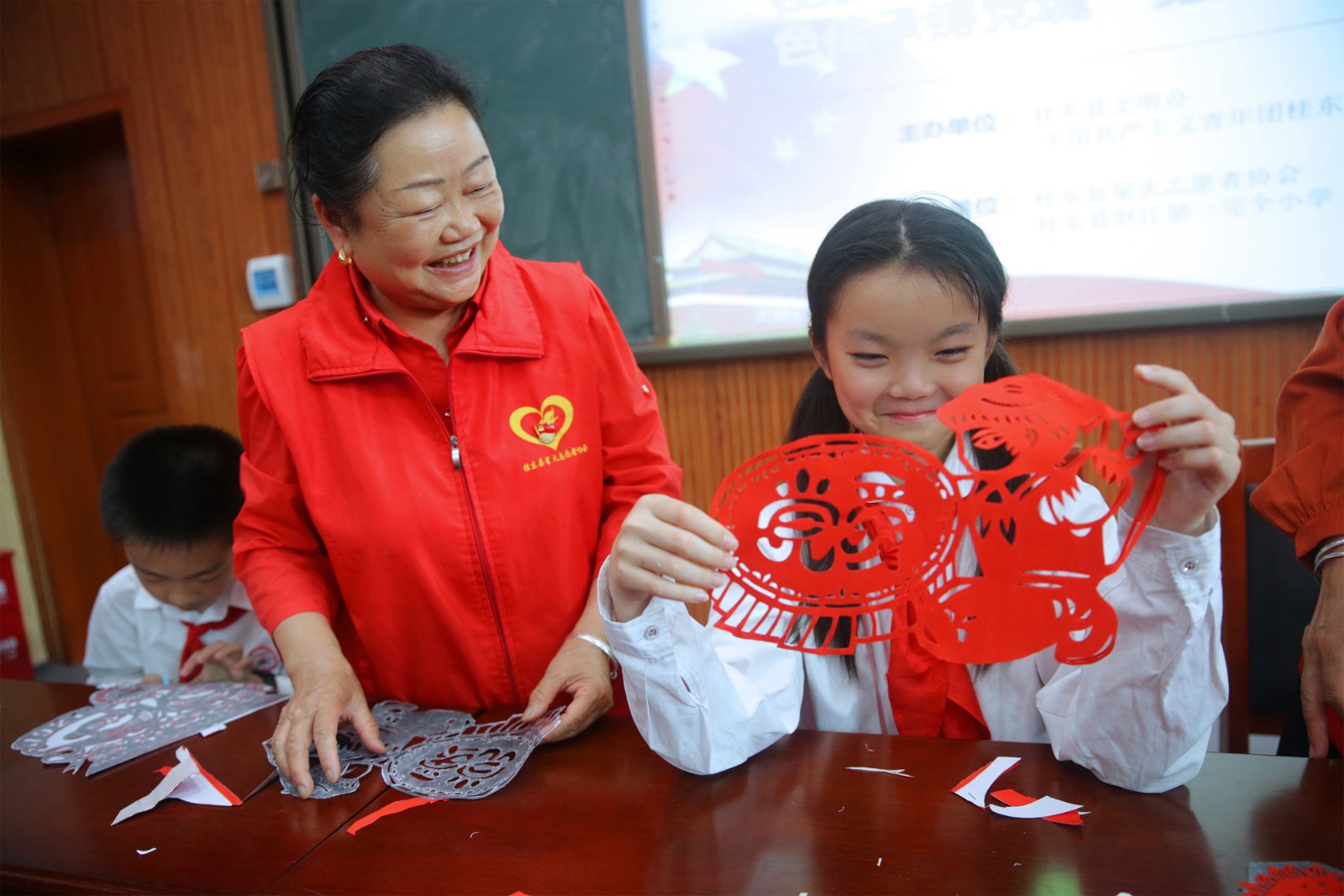 图为2021年6月1日，桂东县沤江一完小阶梯教室，一同学正在展示她刚完成的剪纸作品“爱党”  (1).jpg